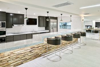 A modern kitchen with a bar area and a stone backsplash.